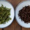 Comparison of green tea and black tea leaves infused in two bowls.