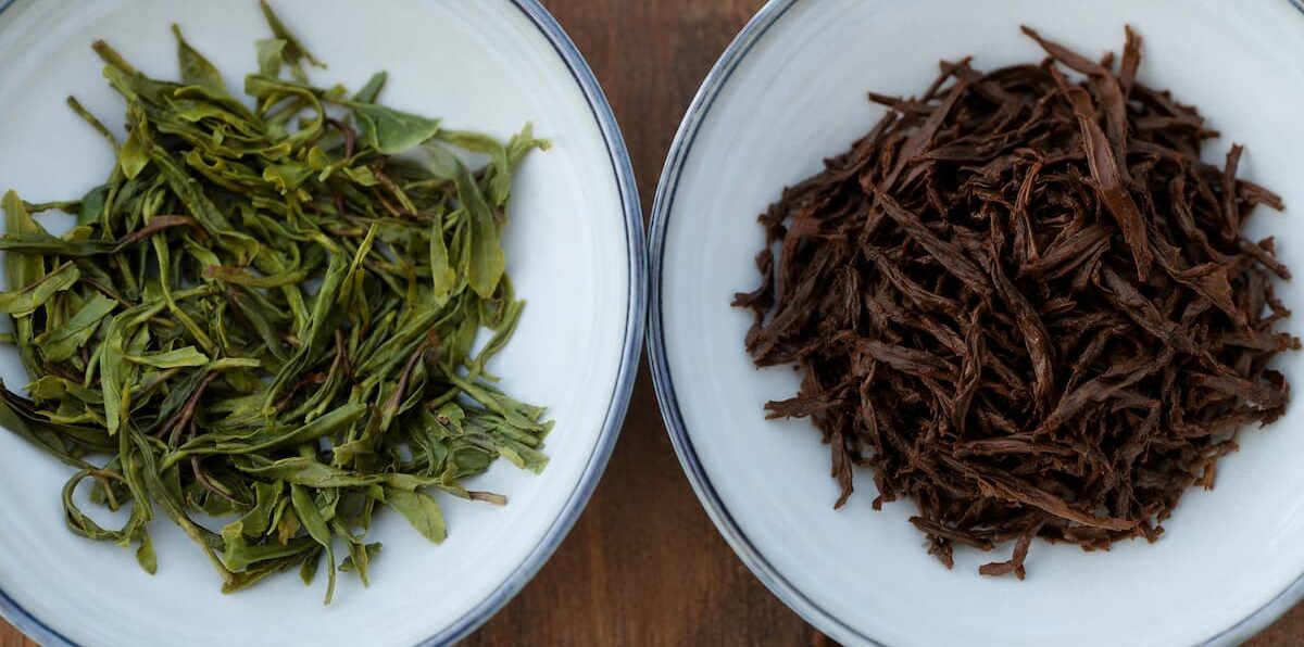 Comparison of green tea and black tea leaves infused in two bowls.