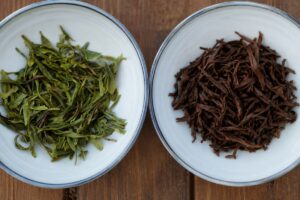 Comparison of green tea and black tea leaves infused in two bowls.